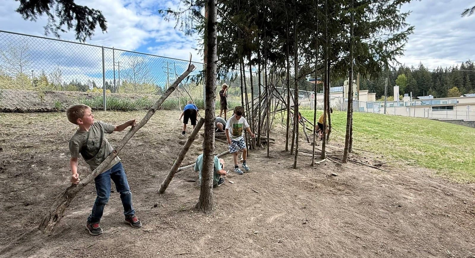 Children building a stick fort under the pines at Shuswap Kids Club